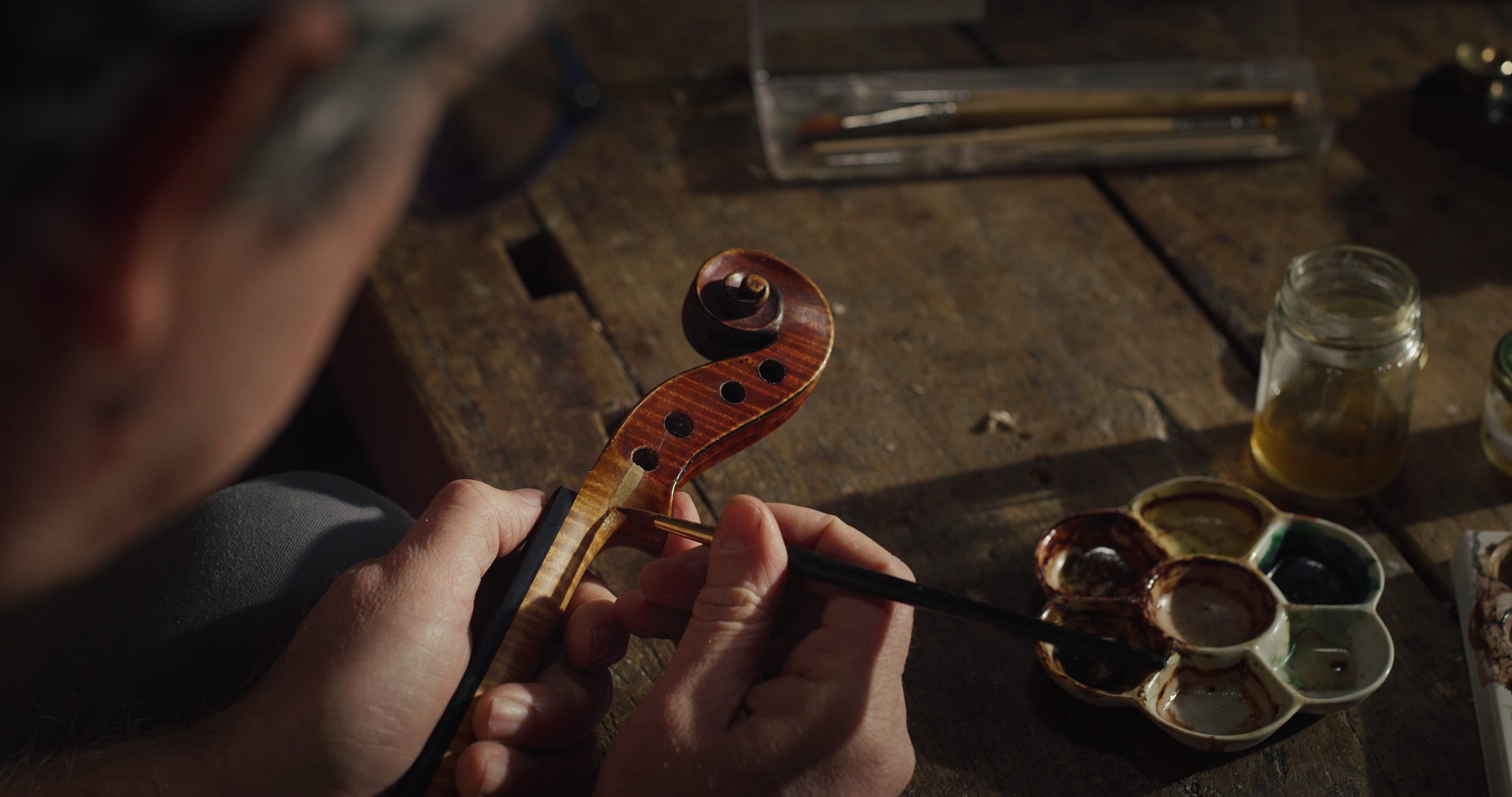 hands painting varnish on to a violin