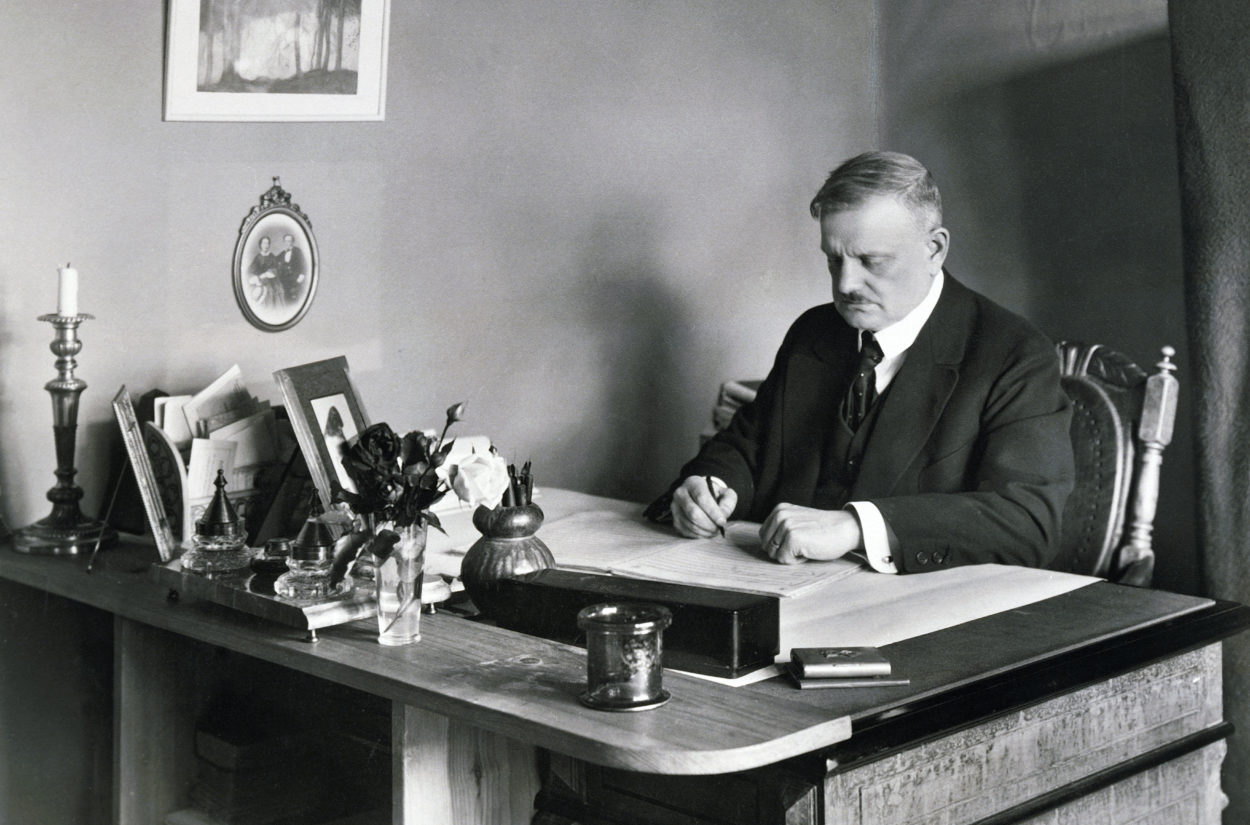 A black and white photo of Jean Sibelius sitting in his studio